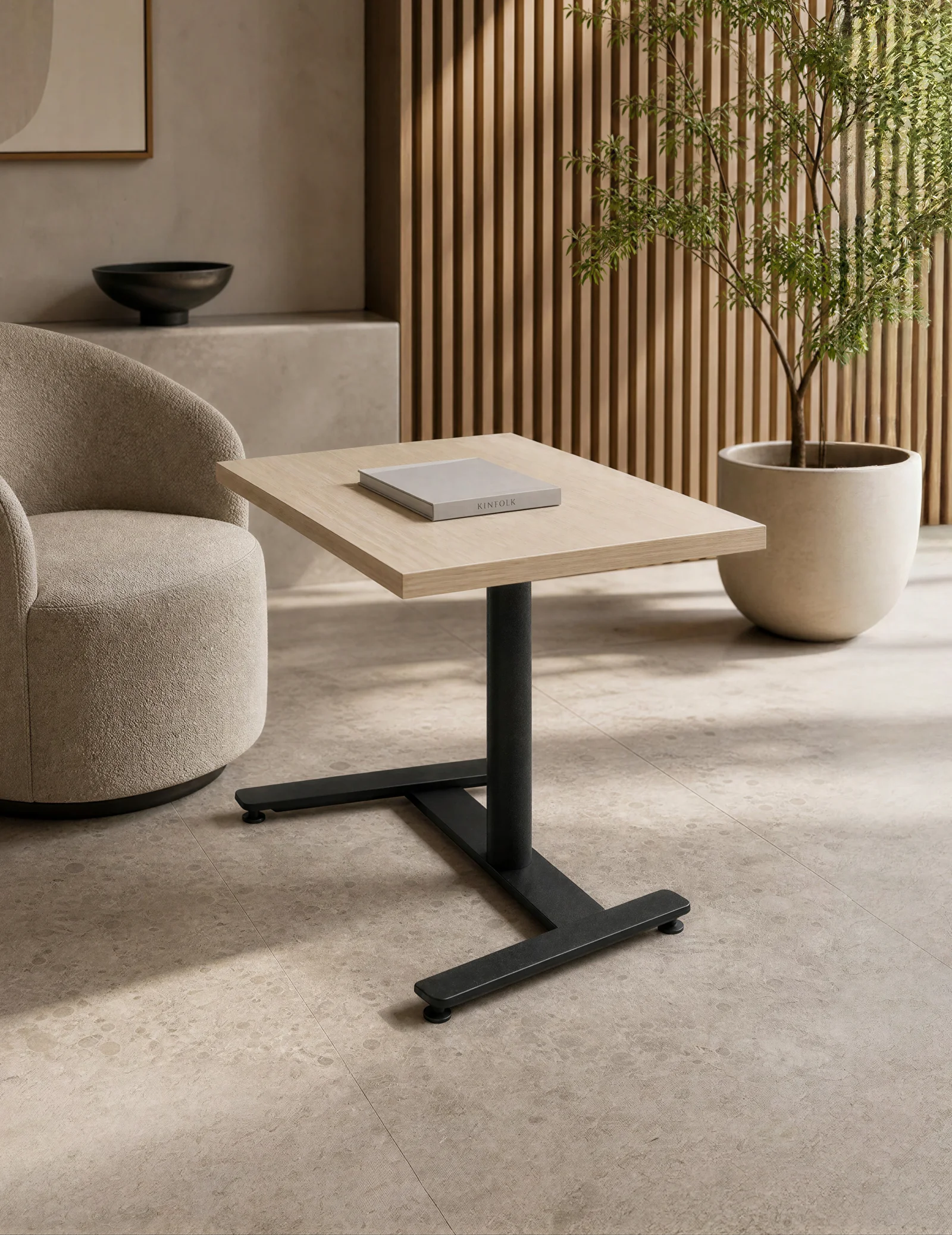 Solo height-adjustable side table with a light oak top and black pedestal base beside a boucle lounge chair in a sunlit slat-walled lounge