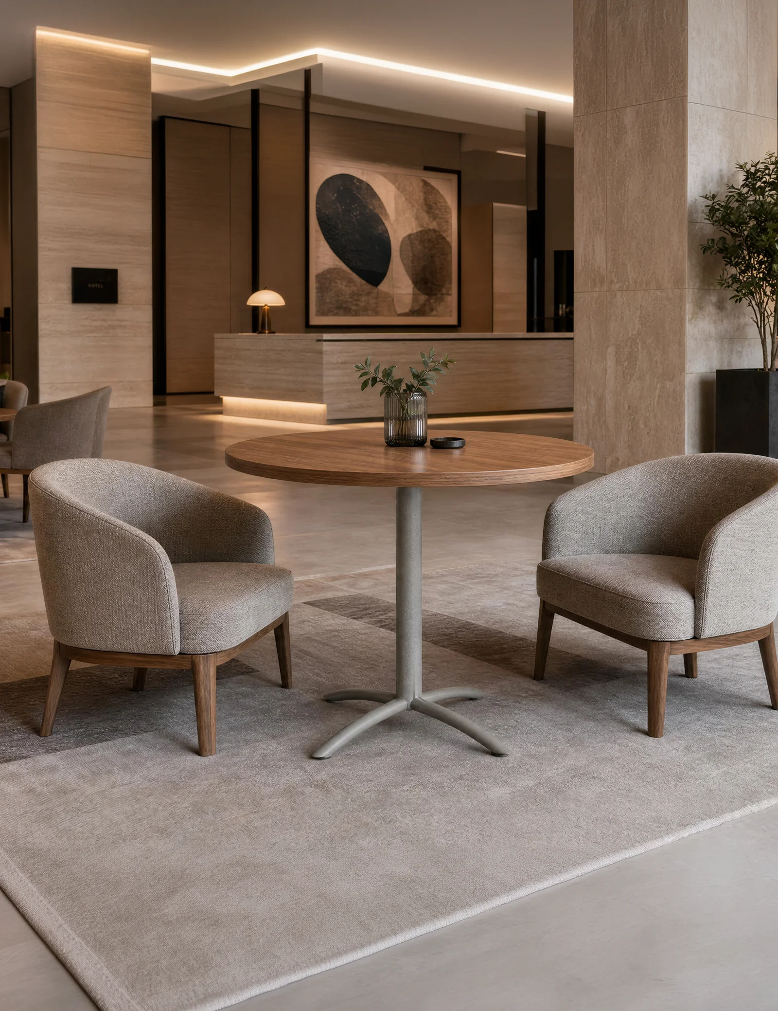Round Stretch pedestal table between two upholstered lounge chairs in a hotel lobby seating area