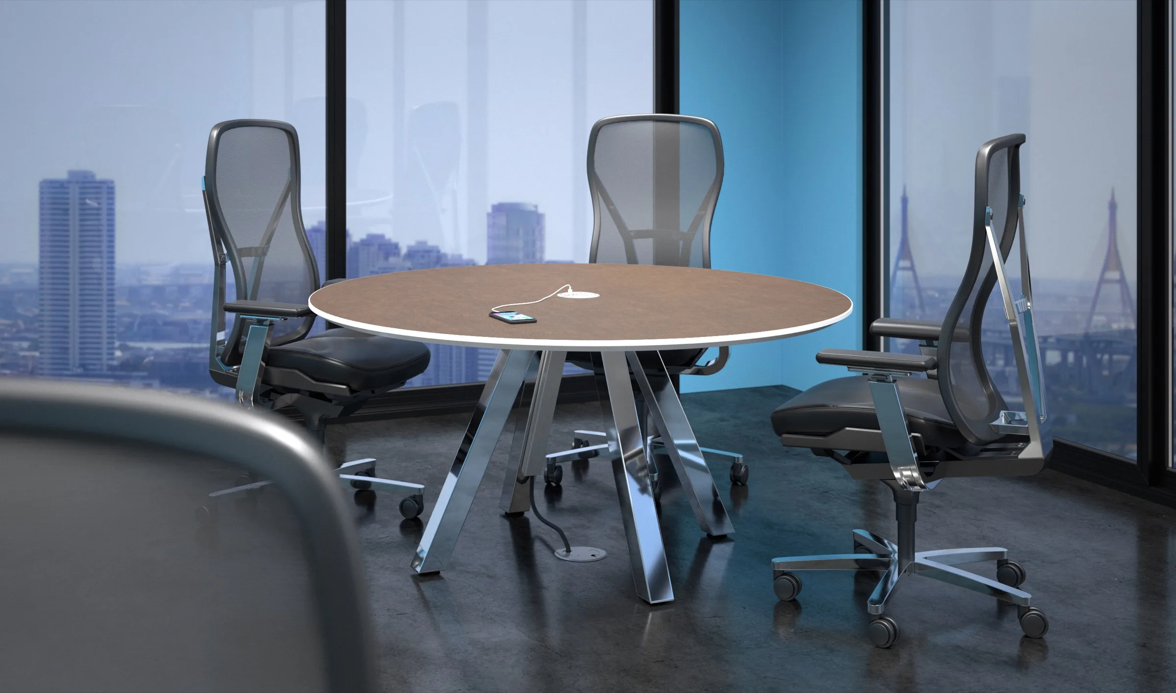Round table with a surface power unit charging a phone, its cord routed through a floor grommet, in a high-rise meeting room